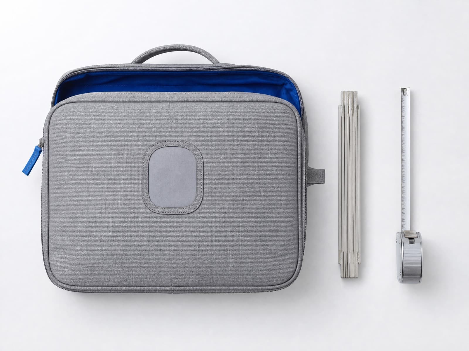 A cabin bag laid flat beside a folding rule and a steel tape measure